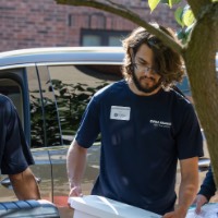 2 GVSU Alumni carrying gray boxes inside